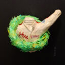 Painted Sculpture. Torso of F1 pilot in white overall with large laurel wreath around his chest. His left arm protrudes triumphantly from the wreath. Recycled paper pulp, painted. Artwork by ©joke van eyck